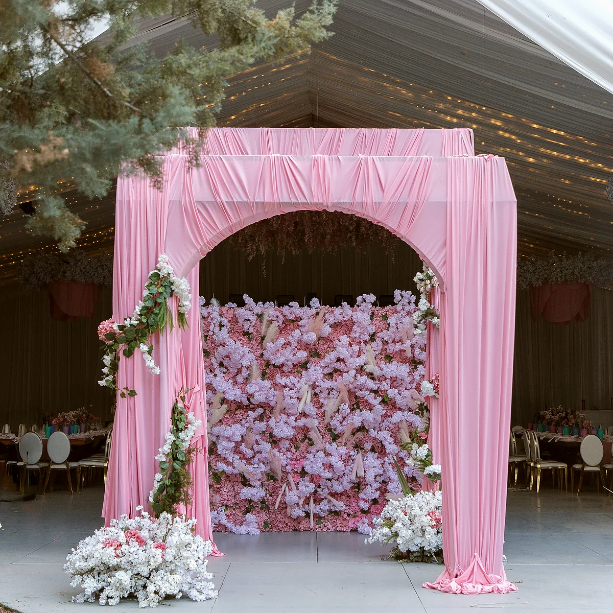 Arco drapeado en rosa con muro de flores