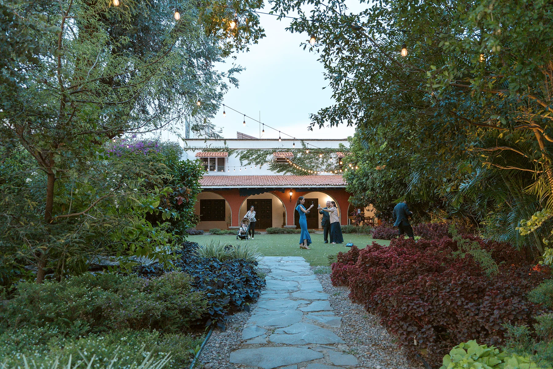 La casona vista desde el jardín al atardecer, con los invitados llegando