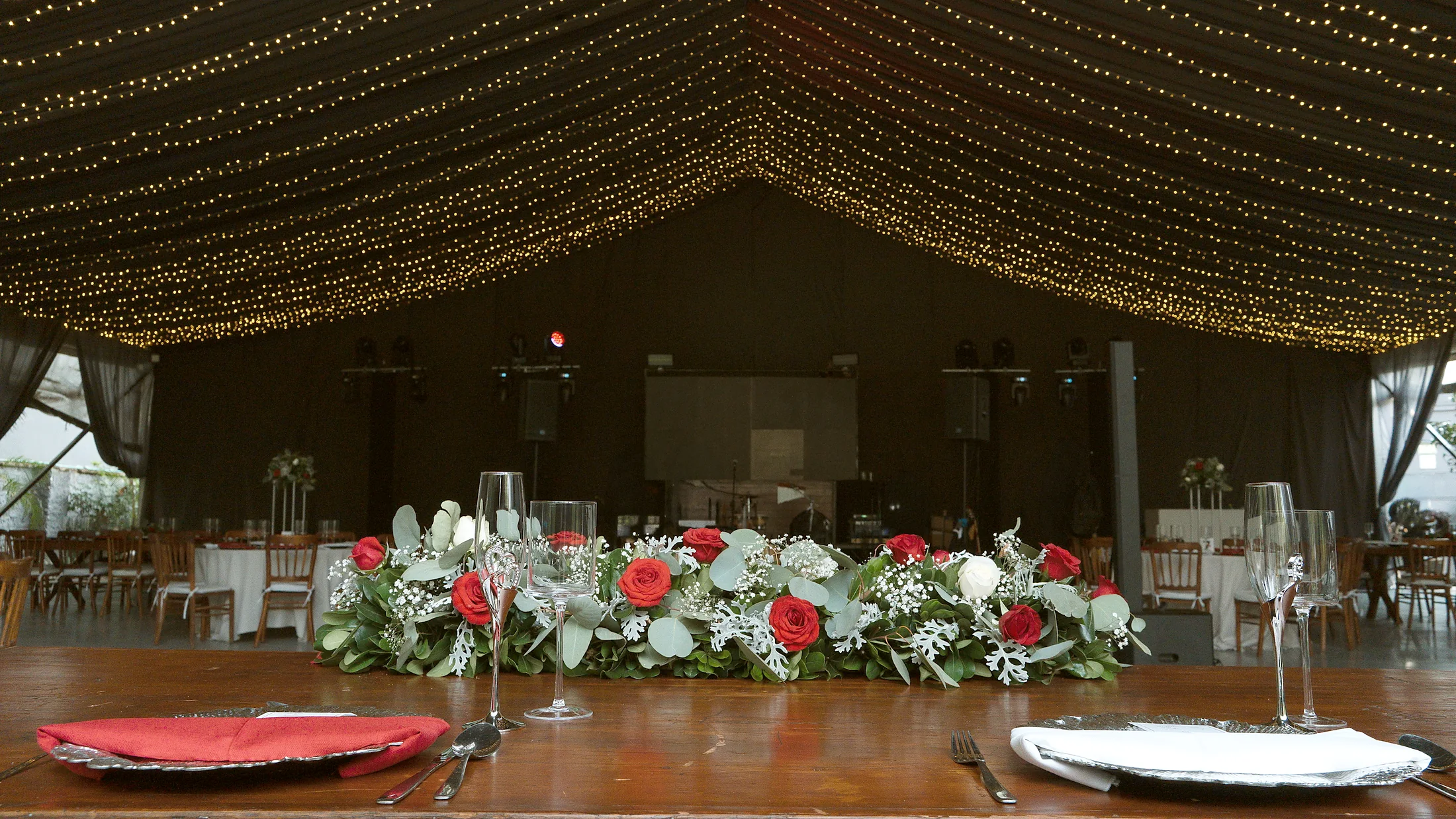 El plafón de luces del pabellón sobre la mesa imperial vestida con flores rojas y blancas